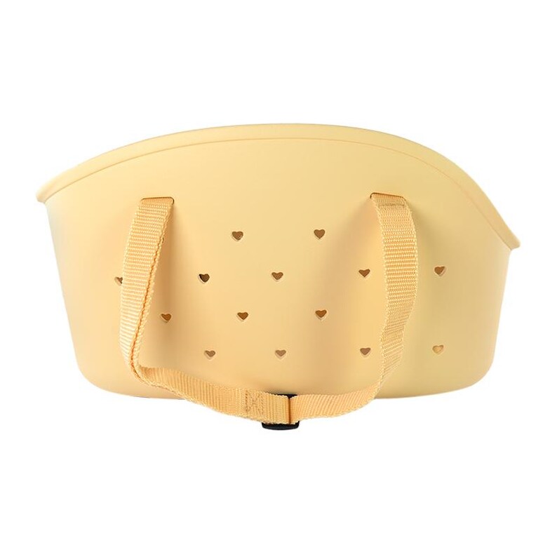 Puede incluir: Una cesta de color amarillo claro con recortes en forma de coraz&oacute;n. Tiene dos asas de tela beige y una correa a juego. La cesta est&aacute; hecha de un material flexible.