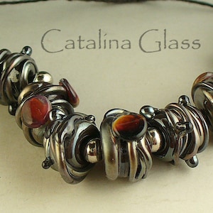 May include: A necklace made of dark gray and brown glass beads with a swirl pattern. The beads are interspersed with smaller silver beads. The necklace is labeled "Catalina Glass".