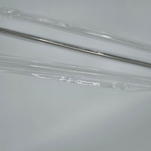 Puede incluir: Dos pajitas de metal plateadas en un paquete de plástico transparente.
