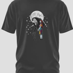 May include: Dark gray t-shirt featuring a graphic of Jack Skellington and Sally from The Nightmare Before Christmas, holding hands in front of a full moon. The design includes stars and is a fan art depiction of the characters.