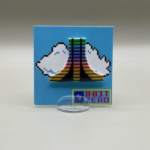 May include: A retro-style 8-bit design on a blue background. The design features a colorful, pixelated arch with white cloud-like shapes on either side. The text "8-BIT ZERO" is displayed in a yellow rectangle.