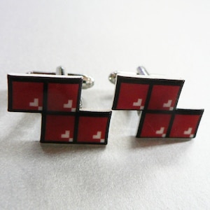 May include: A pair of silver cufflinks with a red and white Tetris block design.