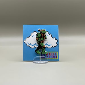May include: A green and orange pixelated figure of a video game character walking on a white cloud. The figure is on a blue background with the text "8-BIT ZERO" in white and purple letters.