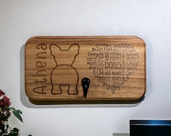 May include: Wooden dog leash holder with a silhouette of a French Bulldog and the name "Athena" engraved on it. The holder has two hooks and is decorated with words related to dogs, such as "muddy paws", "best friend", and "wet noses".