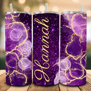May include: Purple and gold glitter tumbler with a swirling abstract design and the name "Hannah" written in gold lettering.
