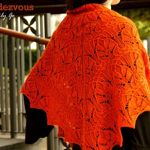 May include: A bright orange knitted shawl with a lacy pattern. The shawl is draped over a person's shoulders.