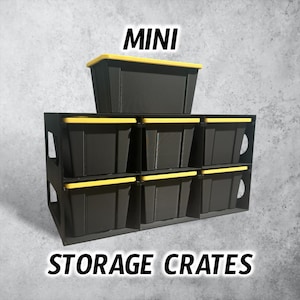 May include: A black storage rack holding six small black bins with yellow lids, with one additional bin placed on top. The text MINI STORAGE CRATES is displayed in black letters. The unit features side cutouts and a structured grid design.