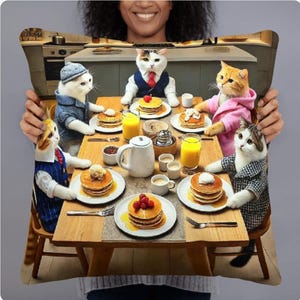May include: A group of cats dressed in clothing are sitting around a table eating pancakes. The cats are wearing a variety of outfits, including a pink hoodie, a blue suit, and a white shirt with a tie. The table is set with plates of pancakes, glasses of orange juice, and a pitcher of milk.