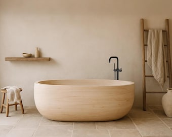 May include: A light-colored wooden bathtub with a rounded shape dominates the scene. A black faucet is mounted on the wall. A wooden ladder with a towel, a small wooden stool, and a shelf with a bowl and a vase complete the spa-like setting.