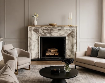 以下が含まれることがあります： 大理石の暖炉、黒い丸いコーヒーテーブル、2つのベージュのアームチェアがあるリビングルーム。ベージュのソファと柄のラグがシーンを完成させています。暖炉には花瓶と花が飾られています。
