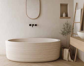 May include: A modern bathroom with a light wood oval bathtub, a matching oval mirror, and a wooden ladder for towels. The walls are a neutral beige, and the floor is light wood. A small olive tree in a basket adds a touch of greenery.