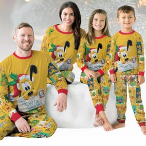 May include: Matching family Christmas pajamas in yellow with red trim. Each set features Pluto holding a letter addressed "To Santa, North Pole." The pants have a festive pattern with holiday imagery.