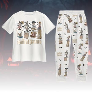 May include: White pajama set with a short-sleeved top and matching trousers. The top features "The Haunted Mansion" text and cartoon characters. The trousers have a repeating pattern of the same characters and bats.