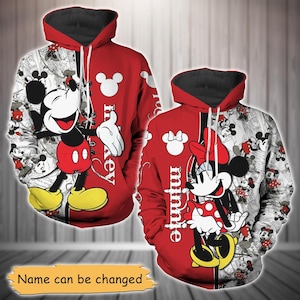 Puede incluir: Sudaderas con capucha rojas y blancas con Mickey y Minnie Mouse. Una sudadera tiene a Mickey Mouse en la parte delantera, la otra a Minnie Mouse. Los diseños incluyen la imagen del personaje y las palabras "Mickey" y "Minnie". El fondo es un cómic en blanco y negro.