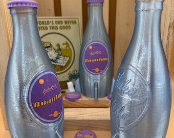 Może przedstawiać: Trzy srebrne butelki Nuka Cola Quantum z fioletowymi zakrętkami i podstawami w kształcie rakiet. Każda butelka ma fioletowo-żółtą etykietę z napisem "Nuka Cola Quantum". Butelki są prezentowane z pasującymi zakrętkami i plakatem w stylu vintage.