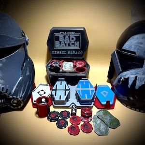 Peut inclure: Un jeu de Kessel Sabacc Star Wars: The Bad Batch. L'ensemble comprend une boîte hexagonale noire, des pièces de jeu, des dés et des jetons rouges et noirs. Deux casques sont de chaque côté du jeu.