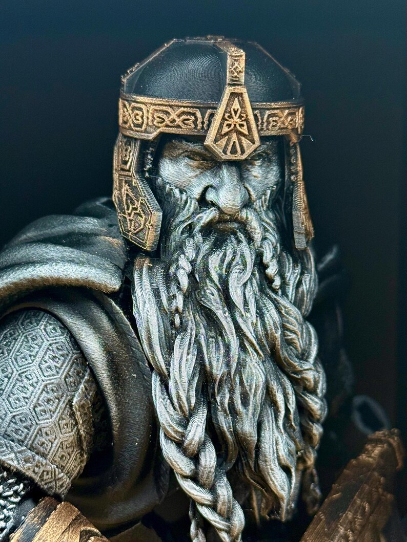 May include: A detailed bust of a dwarf warrior with a long, braided beard and a helmet. The helmet and decorative trim are gold-colored, while the face and beard are a lighter gray. The warrior's armor is visible on the shoulders.