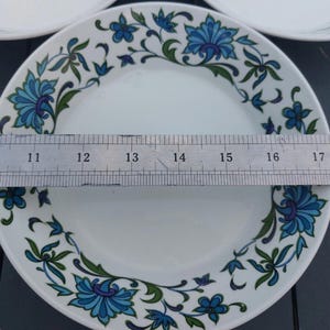 Op de afbeelding: Een wit keramiek bord met een blauw en groen bloemenpatroon. Het bord heeft een diameter van 30,5 cm.