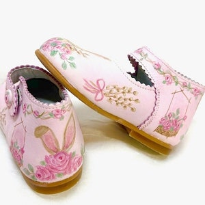 Shoes are in a stacked position. One shoe shows the pussy willows, and a basket of roses.  The other shoe shoe displays the back bunny ears and a peek at the rose basket on the sides.