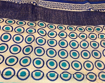 May include: A cream-colored fabric with a blue and teal circle pattern. The fabric has a blue and white border with a geometric design.