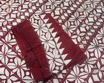 Può includere: Un tessuto bordeaux scuro con un intricato motivo geometrico ricamato in bianco, composto da forme ripetute di rombi e stelle. Il tessuto presenta un design denso cucito a mano con un bordo prominente di triangoli bianchi lungo il lato.