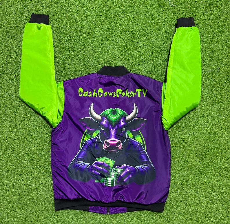May include: A purple and lime green bomber jacket featuring a graphic on the back of a bull with green hair holding stacks of cash. The text CashCowsPokerTV is printed in lime green above the bull illustration. The jacket has long lime green sleeves.