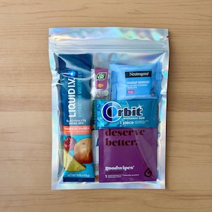 Puede incluir: Una bolsa transparente hologr&aacute;fica con varios art&iacute;culos peque&ntilde;os. Incluye un sobre de mezcla de bebida electrol&iacute;tica Liquid I.V., caramelos Tic Tac, una toallita desmaquillante Neutrogena, chicle Orbit wintermint y una toallita goodwipes de agua de rosas.