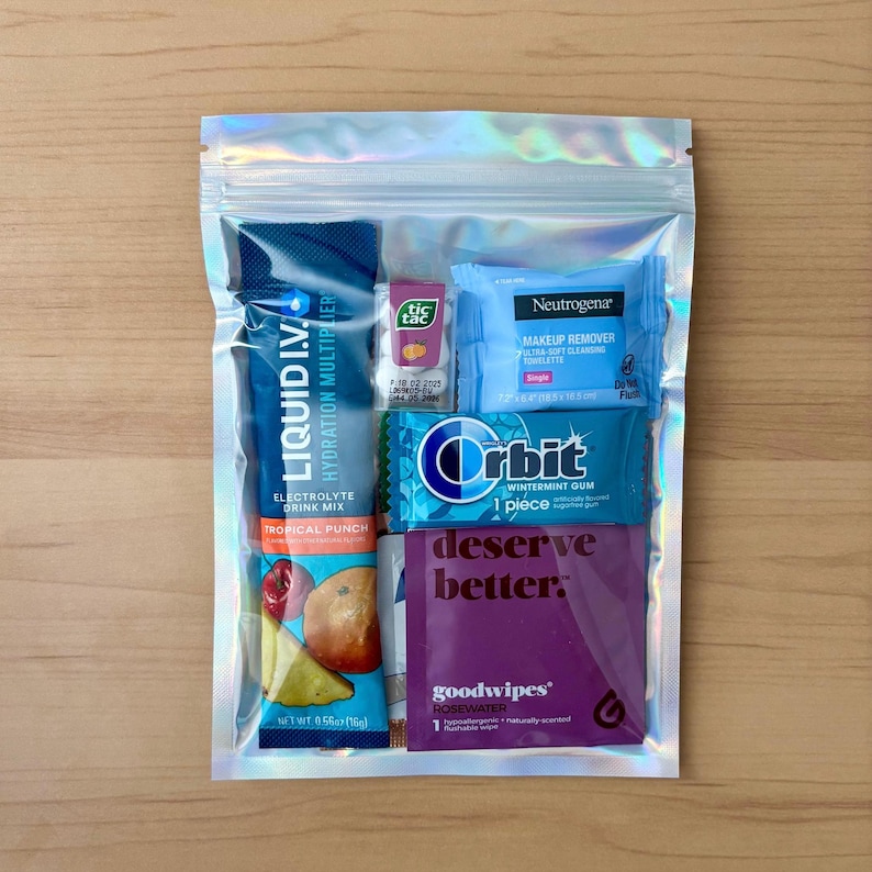 Puede incluir: Una bolsa transparente hologr&aacute;fica con varios art&iacute;culos peque&ntilde;os. Incluye un sobre de mezcla de bebida electrol&iacute;tica Liquid I.V., caramelos Tic Tac, una toallita desmaquillante Neutrogena, chicle Orbit wintermint y una toallita goodwipes de agua de rosas.