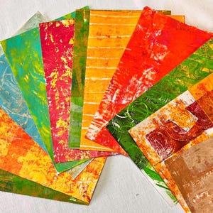 May include: A collection of colorful, abstract patterned paper sheets. The papers are arranged in a fan shape, with the colors ranging from orange, yellow, green, and red.