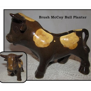 May include: Brown and yellow glazed ceramic bull planter. The bull has a brown body with yellow spots and a brown tail. The planter has a hole in the top for planting.