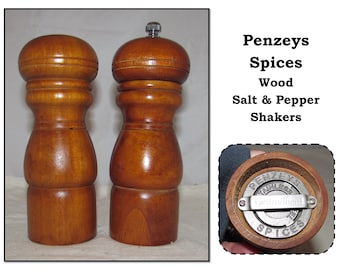 May include: A set of two wooden salt and pepper shakers with a stainless steel grinder mechanism. The shakers are labeled "Penzzeys Spices" and "Gourmet Salt".