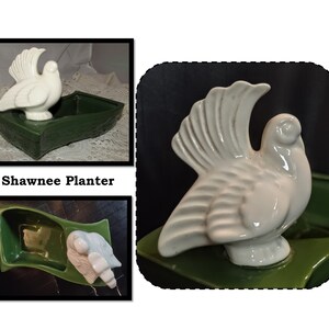 May include: A white ceramic dove figurine atop a green rectangular planter. The dove has detailed wing feathers and a smooth body. The planter is a deep green color. The text "Shawnee Planter" is visible.