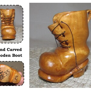 May include: Hand-carved wooden boot with a light brown finish. The boot features a rounded toe, a laced-up front, and a small handle. The text "Hand Carved Wooden Boot" is visible in the image.