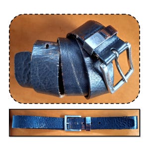 May include: A rolled-up black leather belt with a silver-colored buckle. The belt shows signs of wear and tear, with visible creases and a worn appearance. The buckle is rectangular with a classic design.