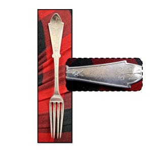 May include: A silver fork with a decorative handle and four tines. The handle has an ornate design with the word "Diggrie" engraved on it. The fork is set against a red and black plaid background.
