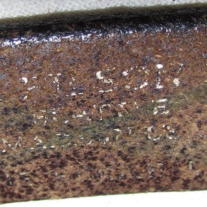 May include: Close-up of a brown leather belt with the text "FULL GRAIN LEATHER MADE IN U.S.A." embossed on the surface.