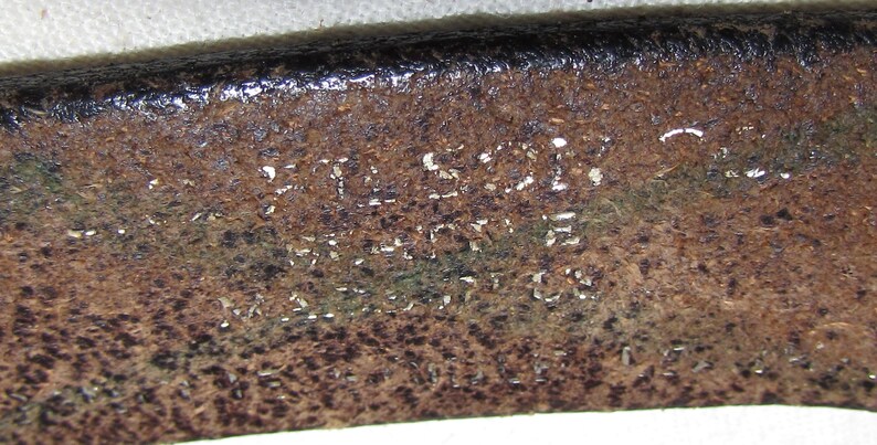 May include: Close-up of a brown leather belt with the text "FULL GRAIN LEATHER MADE IN U.S.A." embossed on the surface.