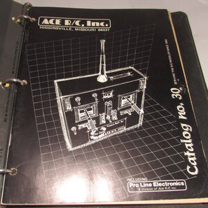 Puede incluir: Portada de cat&aacute;logo negra con un patr&oacute;n de cuadr&iacute;cula blanca y una ilustraci&oacute;n detallada de un transmisor de radiocontrol. El texto "ACE R/C, Inc." y "Catalog no. 30" son visibles. Incluye la divisi&oacute;n "Pro Line Electronics".