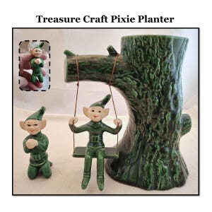 Puede incluir: Un macetero de cerámica verde con forma de tronco de árbol con dos duendes de cerámica verde. Un duende está sentado en un columpio y el otro está arrodillado en el suelo. El macetero está etiquetado como "Treasure Craft Pixie Planter".