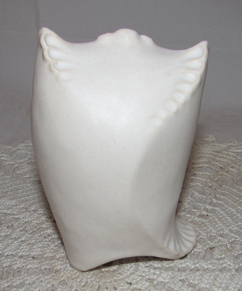 May include: White ceramic owl sculpture with a smooth, rounded body and detailed wings. The owl is perched on a white surface.