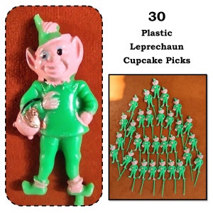May include: Thirty plastic green leprechaun cupcake picks. Each pick features a small leprechaun figurine with a pink face, green hat, and green clothing. The leprechauns are holding a pot of gold.