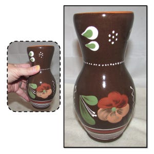 May include: A brown ceramic vase with hand-painted flowers in shades of red, orange, and green. The vase has a white rim and a white dotted pattern around the base.