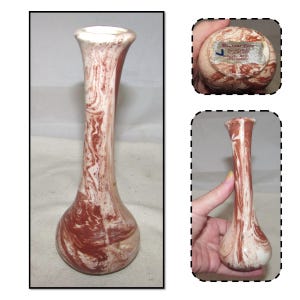 May include: A small, white and brown marbled ceramic vase with a narrow neck and a rounded base. The vase has a label on the bottom that reads "Mountain Clay Pottery, Flagstaff, AZ, Made in USA".