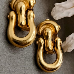 May include: A pair of gold-toned door knocker style clip-on earrings.