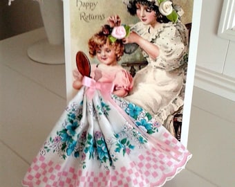 Peut inclure: Une carte faite à la main avec une image vintage de deux filles. La carte est décorée d'un mouchoir rose et blanc à imprimé floral bleu. Le texte sur la carte est "Many Happy Returns".