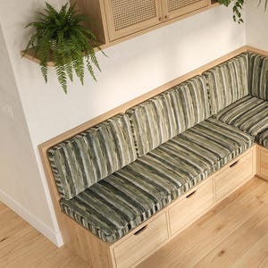 May include: A light wood corner bench featuring built-in storage drawers and thick seat cushions upholstered in a vertical striped fabric with shades of olive green, cream, and dark gray, positioned beneath wall-mounted wooden shelving units.