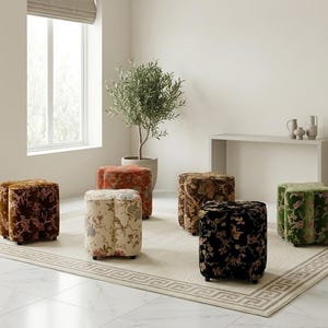 May include: A collection of six clover-shaped ottomans upholstered in velvet fabric with various floral patterns in colors including brown, cream, orange, black, and green, each resting on small black feet and arranged on a rectangular area rug.