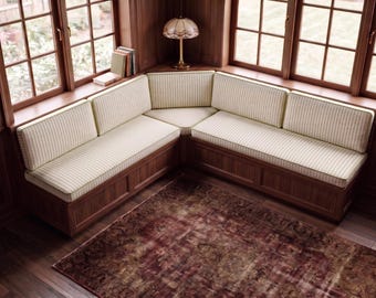 May include: An L-shaped corner bench featuring a dark wood base and cream-colored cushions with thin vertical stripes. The seating arrangement is positioned against a corner with windows, providing a structured and functional furniture piece.