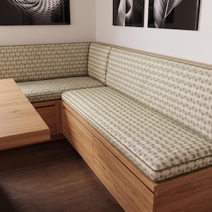 May include: A corner bench seating unit constructed from light-toned wood with integrated storage compartments. The bench features custom-fitted seat and back cushions upholstered in a light green fabric with a repeating white botanical pattern.
