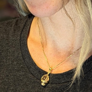 May include: A gold chain necklace with a clear crystal pendant in a gold cage design.